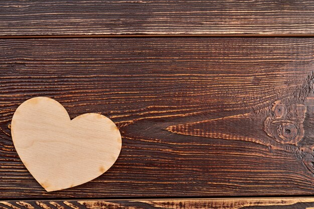 Foto corazón de madera sobre fondo oscuro con textura.