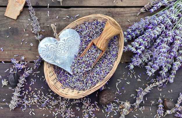 Corazón de metal decorativo en una pequeña canasta llena de lavanda sobre mesa de madera