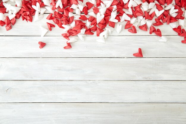 Corazón de papel blanco y rojo sobre madera.