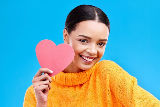 Corazón de papel mujer feliz y retrato sobre fondo azul estudio y telón de fondo Modelo femenino sonrisa y forma de amor confianza y apoyo a la paz gracias y amabilidad en el día de san valentín para el romance