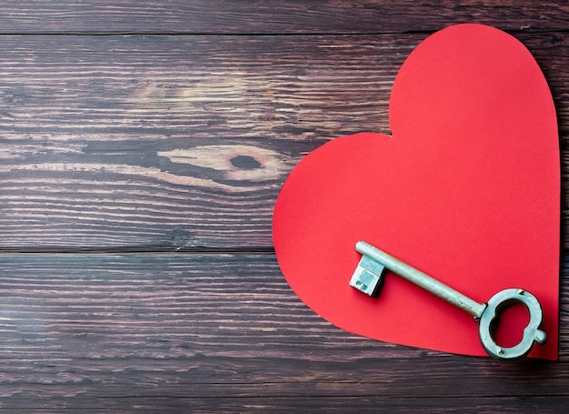 Corazón de papel rojo y llave antigua sobre un fondo de madera oscura Día de San Valentín Copiar espacio