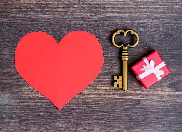 Corazón de papel rojo y llave antigua sobre un fondo de madera oscura Día de San Valentín Copiar espacio