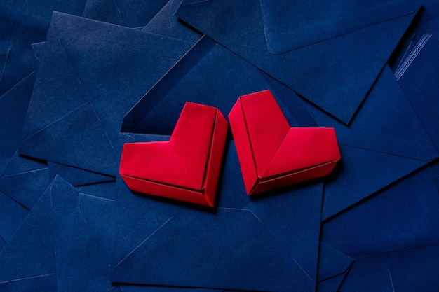 corazón de papel rojo y sobre azul, idea de carta de amor con sobre azul con corazones rojos derramándose.