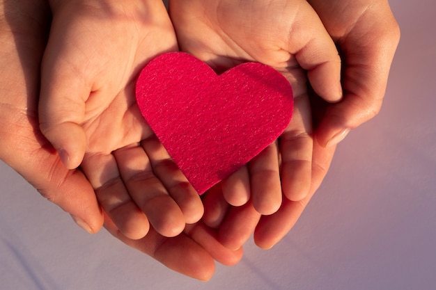 Corazón de papel rosa en la vista superior de las palmas de los niños y mujeres Concepto de familia del día de las madres de amor