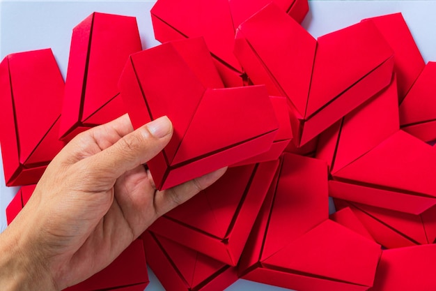 corazón de papelManos sosteniendo un corazón de origami doblado Fondo blancoNiño pequeño mano sosteniendo un corazón rojo