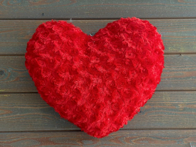 Corazón de peluche rojo en un espacio de pared de madera para el concepto del día de San Valentín