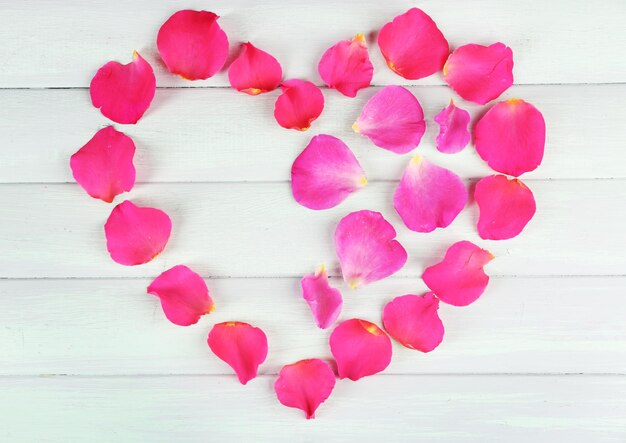 Foto corazón de pétalos de rosa sobre fondo de madera