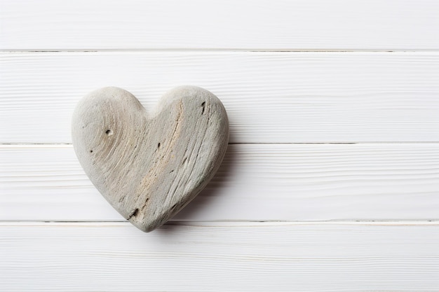 Un corazón de piedra sobre un fondo de madera blanca