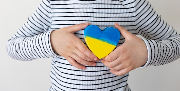 Corazón pintado con los colores de la bandera de ucrania en manos de niños