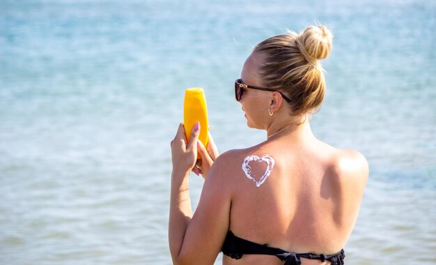 Corazón pintado en la espalda de la niña con crema solar. Descansa junto al mar