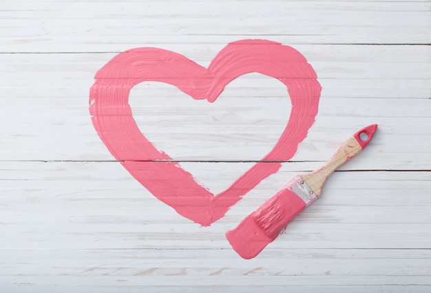 Corazón pintado de rosa en la pared de madera blanca