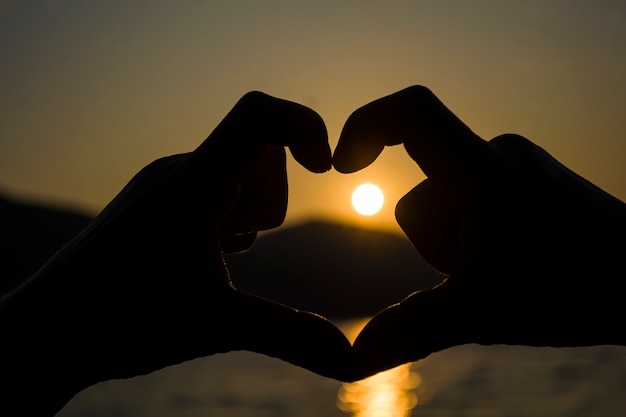 Corazón de la puesta de sol handsevening detrás de la montaña en un gran lago vista romántica de la puesta de sol en el ...