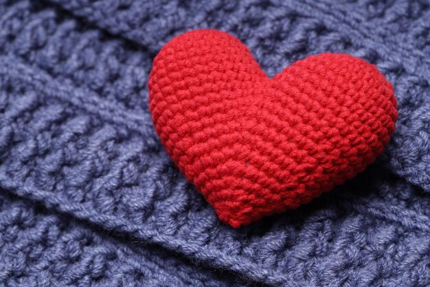 El corazón de punto rojo se encuentra en una servilleta de punto azul. Concepto de amor. Foto de alta calidad