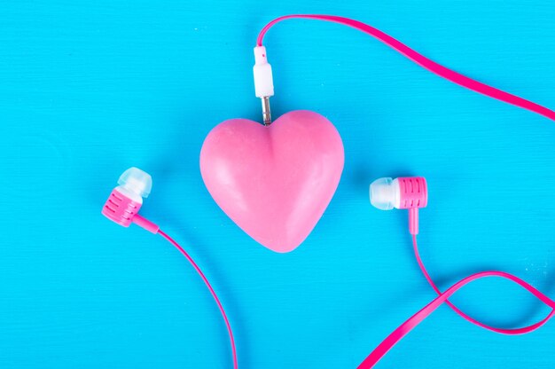 Foto corazón rojo y auriculares sobre un fondo azul concepto de música