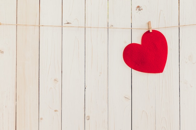 Corazón rojo en blanco colgando de madera blanca con espacio para el fondo de San Valentín y la boda.