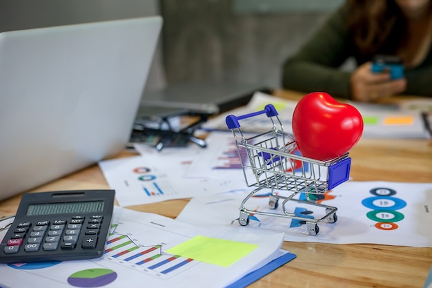 Foto corazón rojo en carrito de compras. gente de negocios que se encuentra trabajando con informes financieros