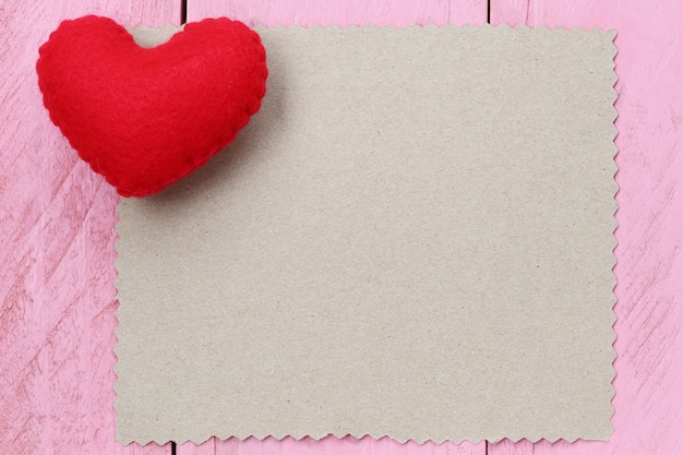 El corazón rojo colocado en la nota de papel de vacío para el texto o el mensaje de entrada en diseño.