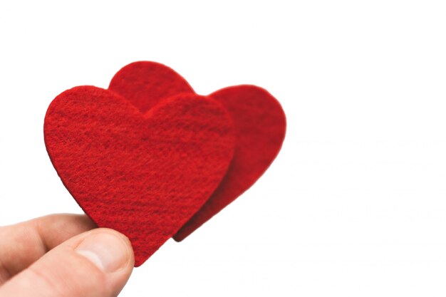 Corazón rojo en los dedos sobre un fondo blanco. día de San Valentín