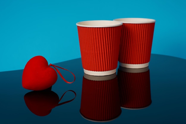 Corazón rojo y dos vasos de papel.