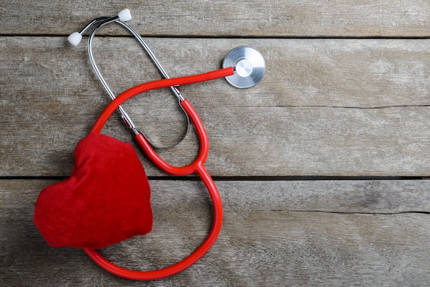 Corazón rojo con un estetoscopio sobre fondo de mesa de madera