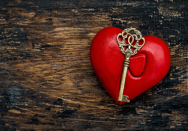 Corazón rojo con llave de oro sobre fondo de madera rústica. Decoración del día de San Valentín