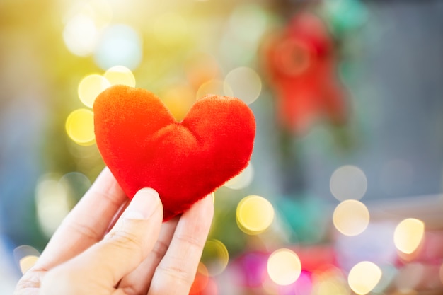 Corazón rojo a mano con el fondo ligero borroso. El amor, la boda y el concepto de san valentín.