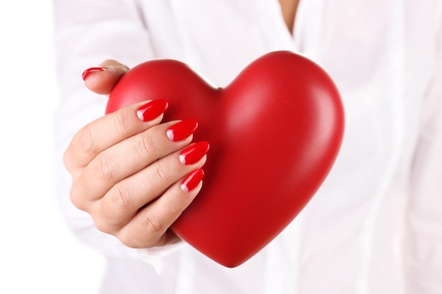 Corazón rojo en la mano de la mujer aislado en blanco