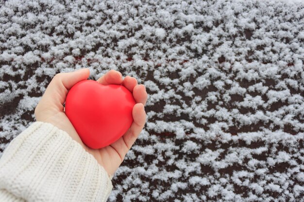 Foto corazón rojo en la mano sobre un fondo nevado