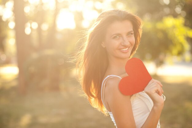 Corazón rojo en manos de una hermosa joven. De cerca