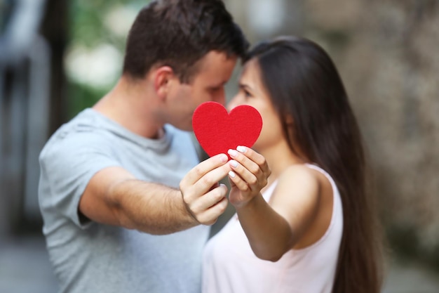 Corazón rojo en manos de una hermosa pareja joven