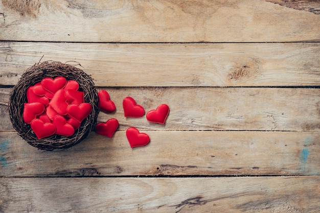 Corazón rojo en el nido sobre fondo de madera con espacio