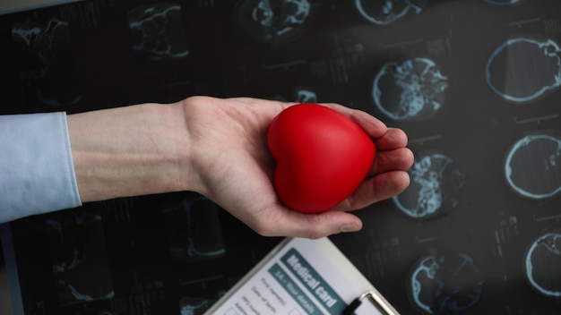 Corazón rojo en la palma de tu mano en el contexto de un concepto de cardiología de tarjeta médica