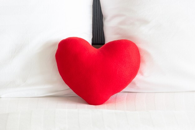 Corazón rojo y Pareja almohada blanca en la cama para el amor, la boda y el concepto de día de San Valentín