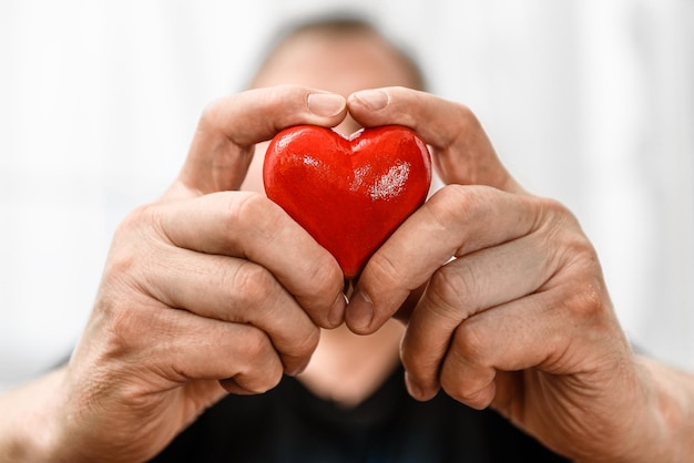 Corazón rojo en el primer plano de la mano de un hombre