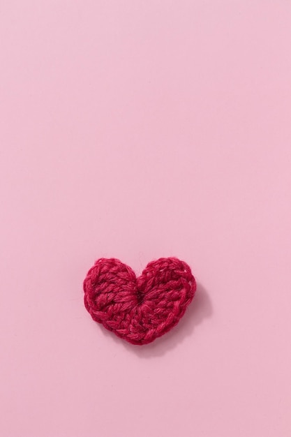 Corazón rojo rosa de amigurumi de ganchillo sobre un fondo rosa Banner de San Valentín