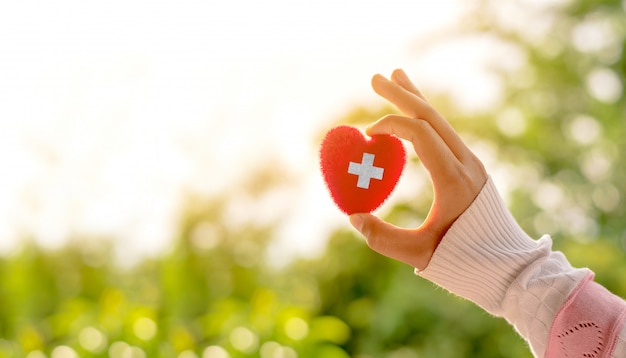 Foto el corazón rojo con el signo de la cruz representa el símbolo del cuidado de la salud.