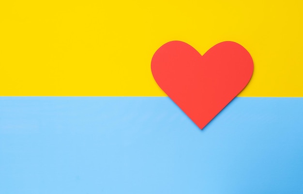 Corazón rojo sobre un fondo amarillo-azul. Vista superior