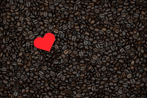 corazón rojo sobre fondo de granos de café concepto de amor foto para el Día de San Valentín los granos de café están dispersos