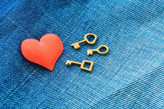 Corazón rojo con tres llaves sobre fondo de jeans