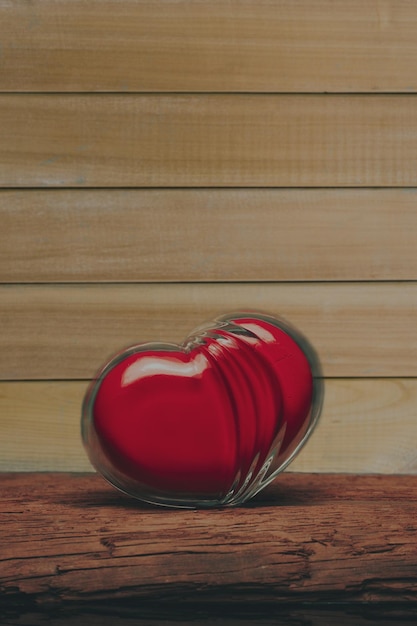 Un corazón rojo de vidrio en una vieja mesa de madera un hermoso fondo oscuro