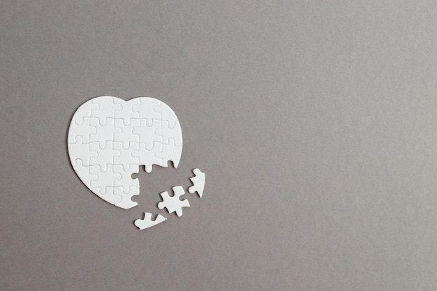 Corazón de rompecabezas blanco sobre fondo de madera gris