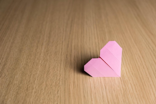 Corazón rosa hecho de origami de papel sobre un fondo de madera Concepto de regalo de San Valentín 14 de febrero Hecho a mano