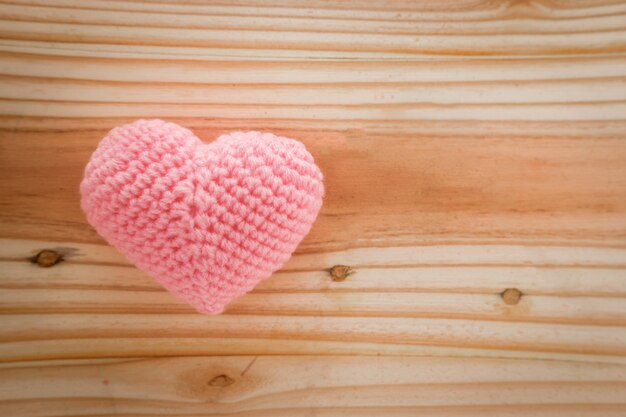 Corazón rosa tejido con hilo en el piso de madera