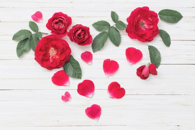 Corazón de rosas en la pared de madera blanca