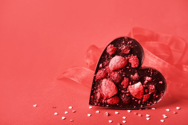 Corazón de San Valentín de chocolate hecho a mano con bayas liofilizadas Símbolo de amor sobre fondo rojo