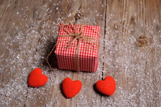 Corazón sobre un fondo de madera con nieve y caja de regalo