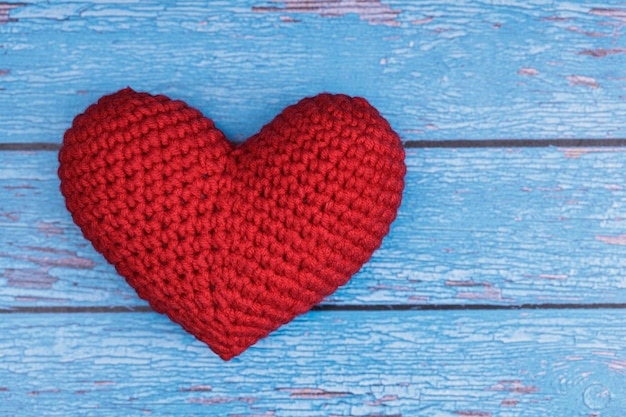 El corazón tejido rojo se encuentra sobre un fondo de textura de madera azul. Concepto de amor. Foto de alta calidad