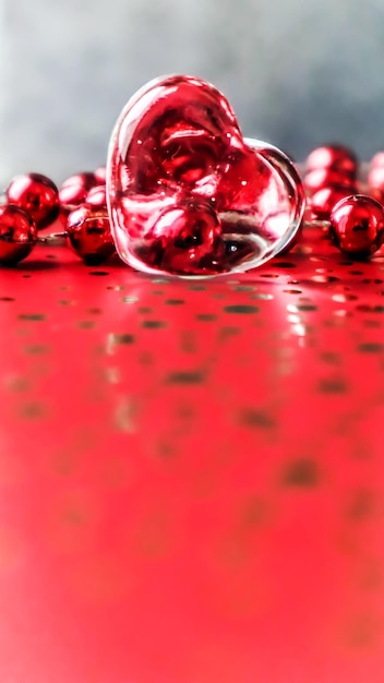 Corazón transparente brillante y un grupo de cuentas rojas Fondo perfecto de la tarjeta de felicitación del Día de San Valentín