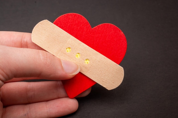 Corazón con vendaje médico yeso en la mano Concepto de problemas de relación