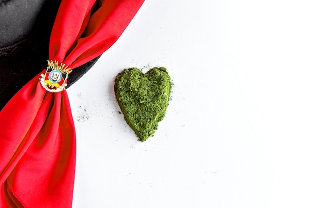 Corazón de yerba mate sobre fondo blanco y pañuelo rojo de gaucho